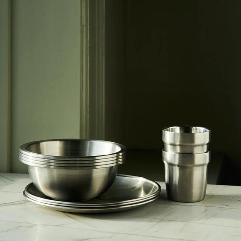 Ståltermokrus og skåle stablet på en marmorbordplade i et minimalistisk design.