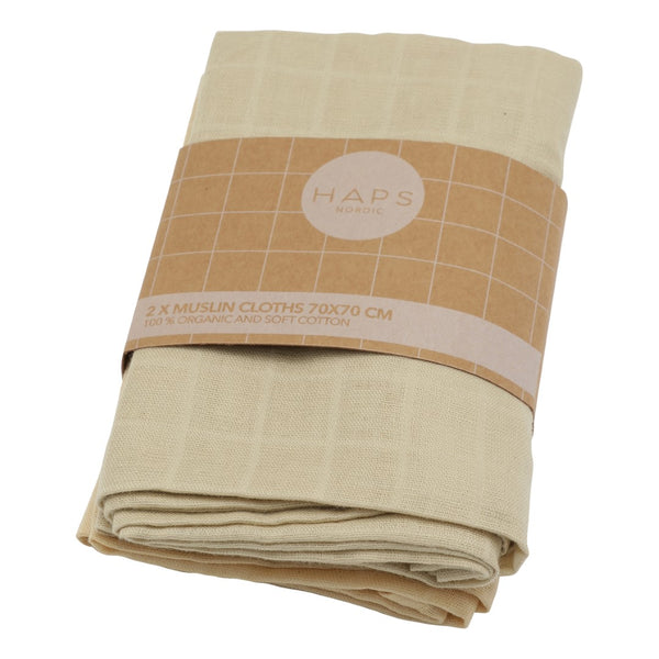 To sammenfoldede muslin stofbleer i en beige farve, pakket med en papiretikette fra HAPS Nordic.