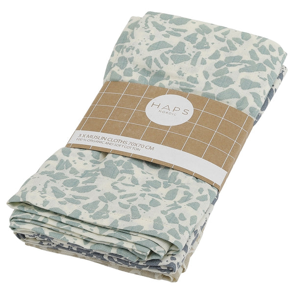 Tre sammenfoldede muslin-klude med et koldt terrazzo-mønster, pakket med en brun papirrem fra HAPS Nordic.